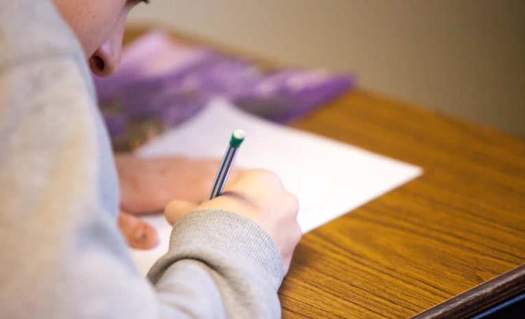 Student writing notes while preparing for an exam, representing how to study for exams effectively