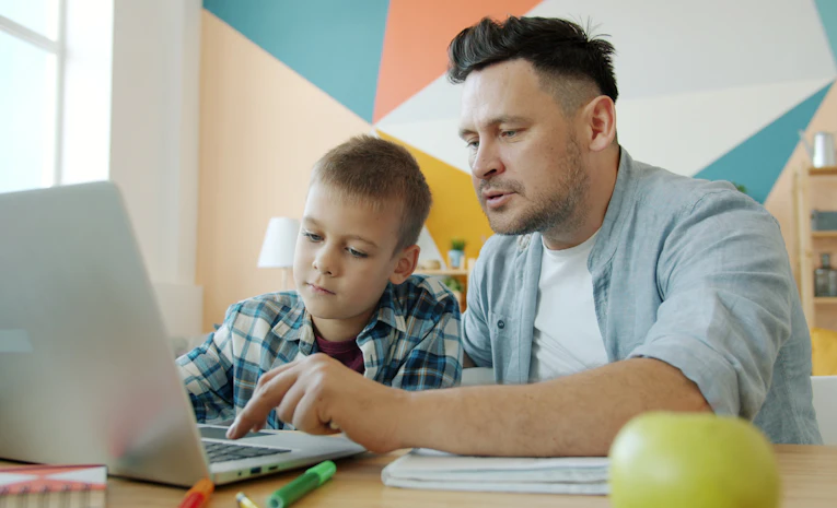 Father and son looking at a laptop together, representing a school learning management system