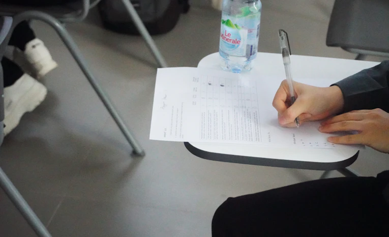 Student writing notes at a desk, representing A level revision