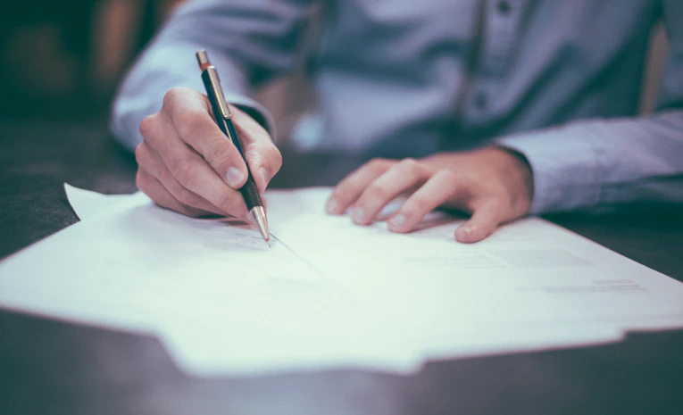 Person filling out a paper application form, representing education grants