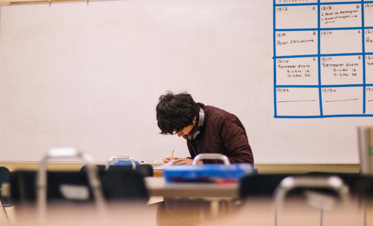 Student writing at a classroom desk, representing a foundation year at university
