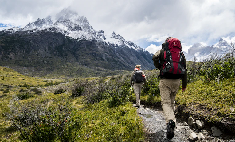 Hikers with backpacks walking toward mountains, representing planning a gap year