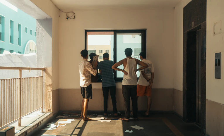 Young people looking out a window together in a college building, representing sixth form vs college