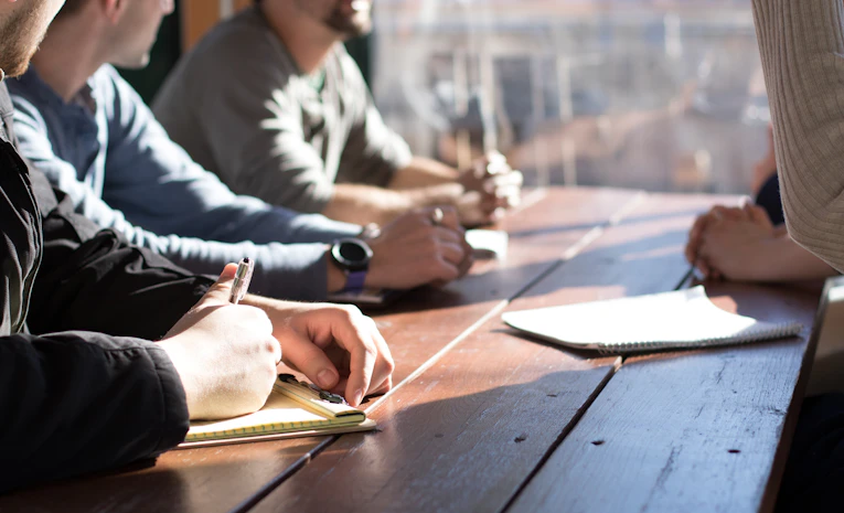 Group of young people in a meeting holding pens, representing student council