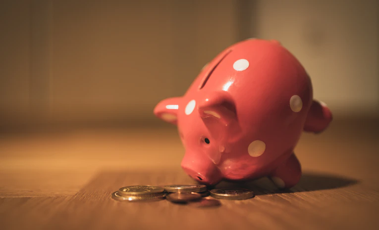Pink piggy bank on a wooden table, representing a student savings account