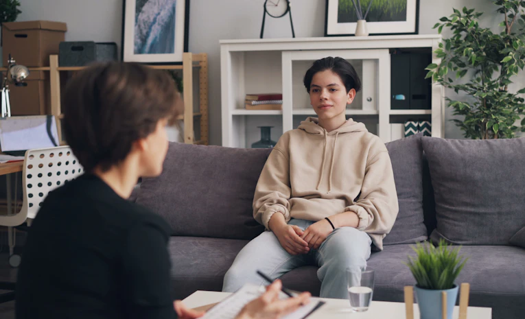 Two people sitting and talking supportively on a couch, representing university mental health support