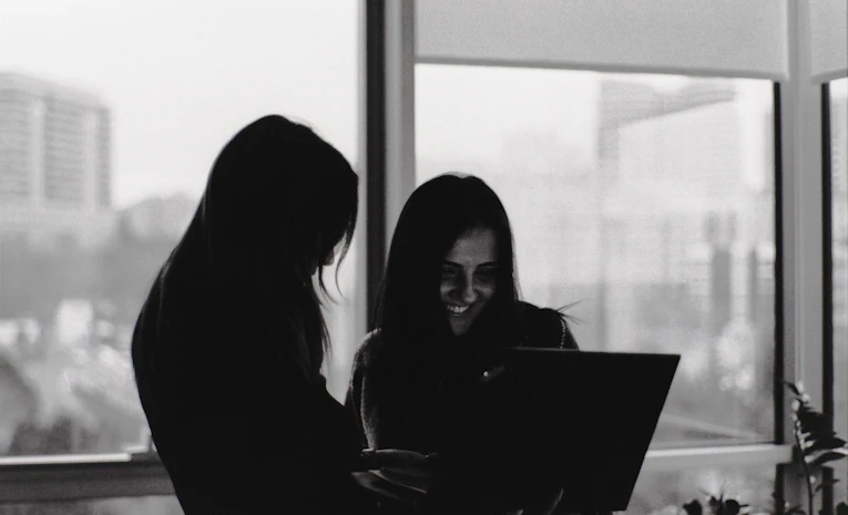 Two people looking at a laptop screen together in a workplace, representing work experience for students